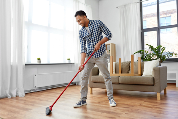 A man sweeping the floor at home